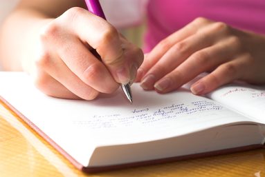 Junge Frau schreibt in ein Notizbuch
