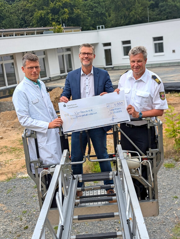 Feuerwehr-Chef Hermann Greven (r.) überreichte im Drehleiterkorb den symbolischen Scheck an Dr. André Schumann (Mitte) und Dr. Joachim G. Eichhorn.