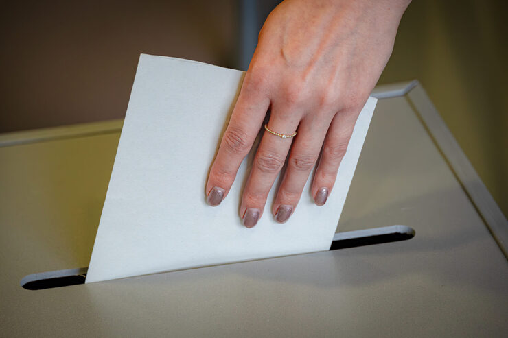 Junge Frau wirft Wahlzettel in Wahlurne