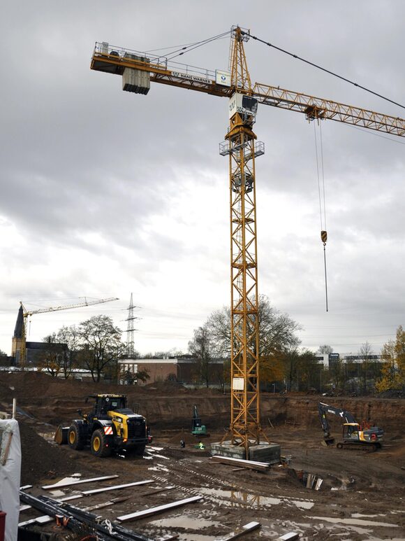 Baumaschinen in der Baugrube, in der Mitte ein Kran