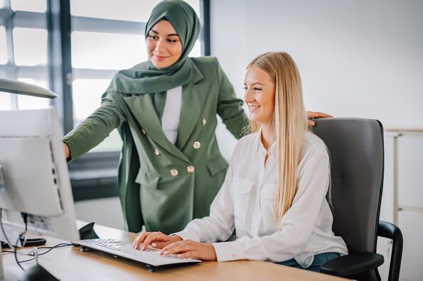 Zwei Frauen arbeiten am Schreibtisch und schauen auf einen Bildschirm