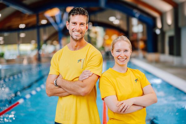 Zwei Personen stehen vor dem Becken im Schwimmbad