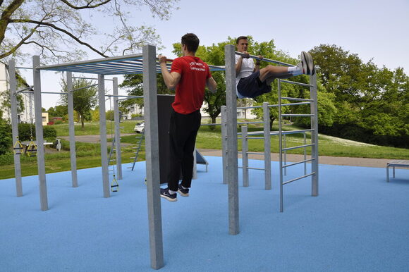 Zwei Athleten trainieren an einer Calisthenics Anlage