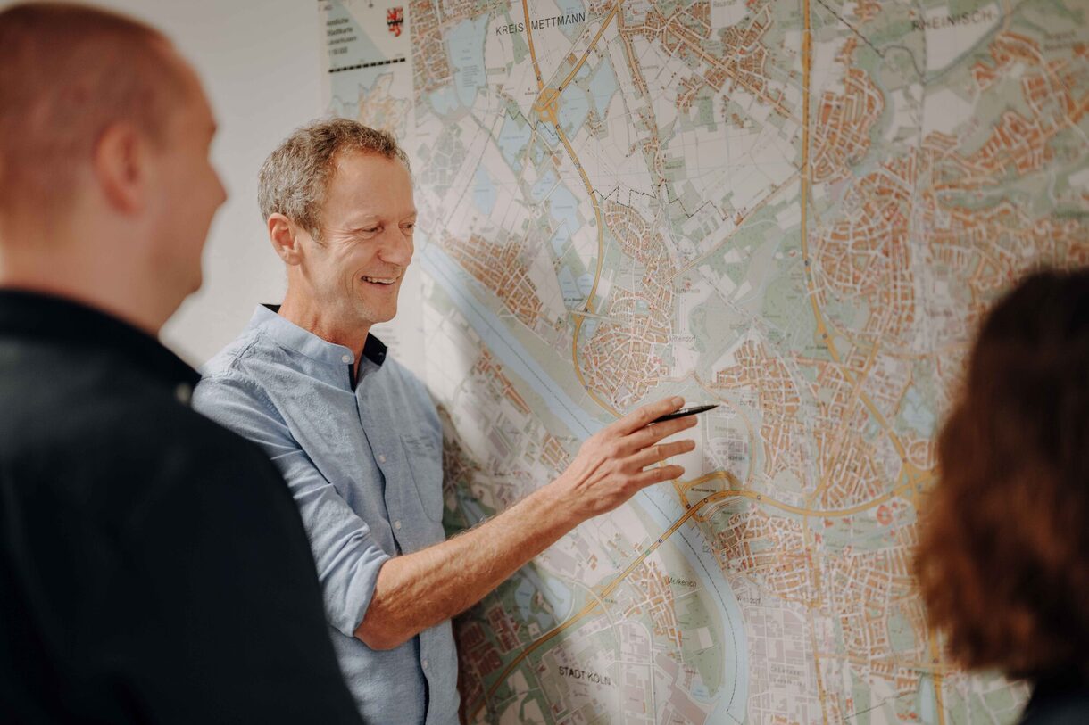 Mitarbeitende aus dem Bereich Kataster & Vermessung vor einem Stadtplan