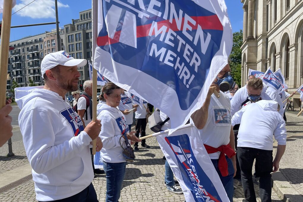 OB Uwe Richrath hält eine Flagge der Kampagne "Keinen Meter mehr!"