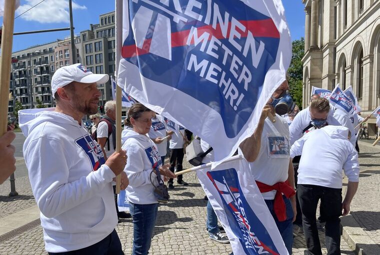 OB Uwe Richrath hält eine Flagge der Kampagne "Keinen Meter mehr!"