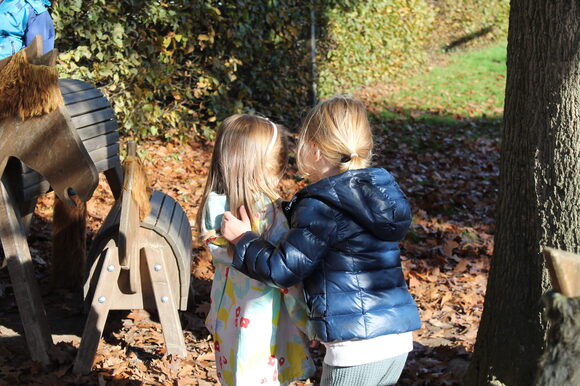 Zwei Kinder stehen im Laub und halten sich im Arm