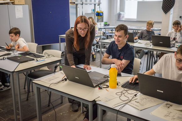 Schülerinnen und Schüler sitzen vor ihren Laptops