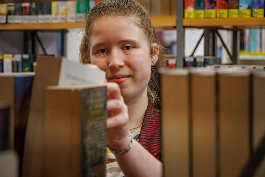 Eine Frau nimmt ein Buch aus dem Regal