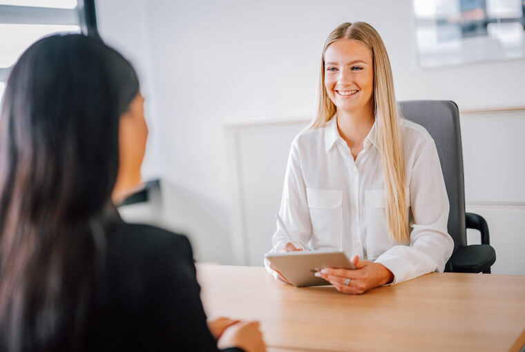 Zwei weibliche Personen sitzen sich am Tisch gegenüber