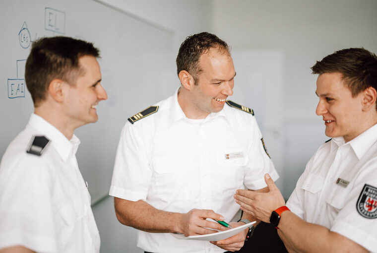 drei Feuerwehrleute in weißem Hemd